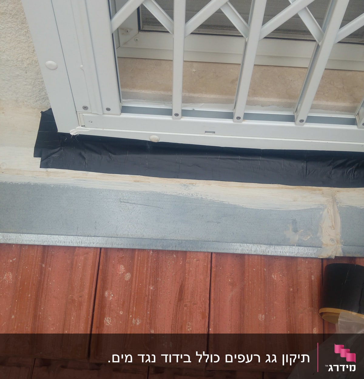 רעפים אדומים עם סרט איטום שחור ליד חלון